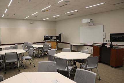 White tables and chairs inside the STEM learning area.