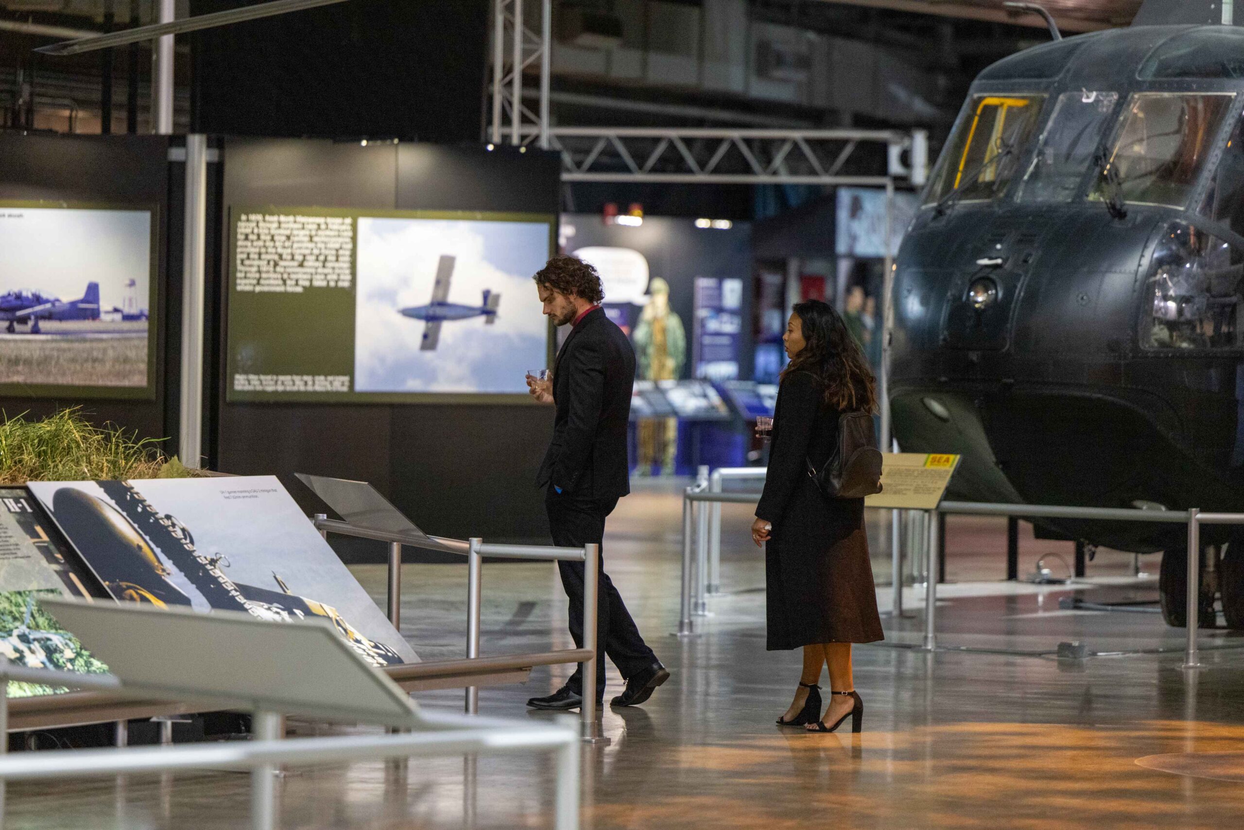 Couple walks through Museum gallery while holding beverages.