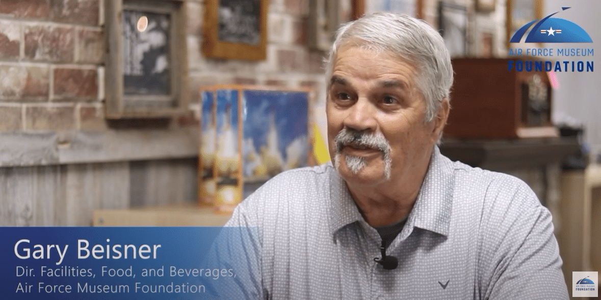 A man sitting in a cafe with text Gary Beisner.