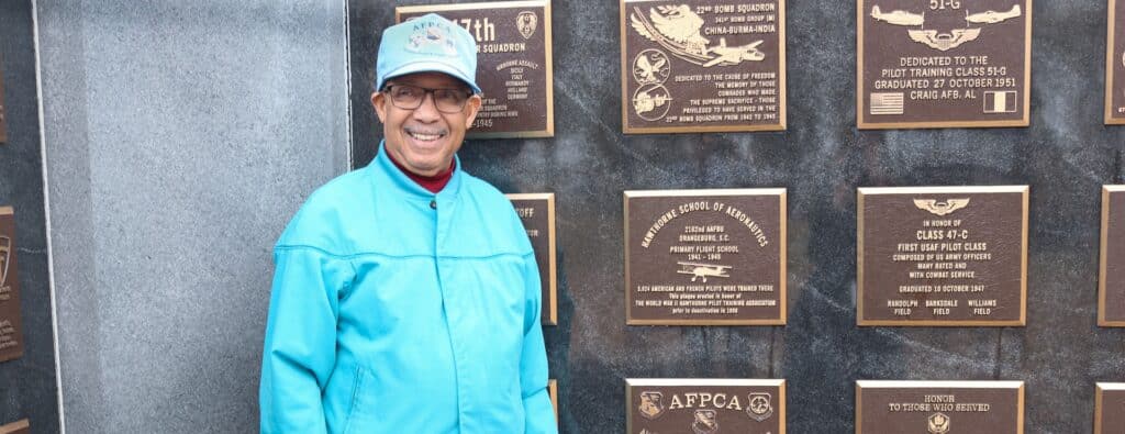 Man in front of plaque wall.